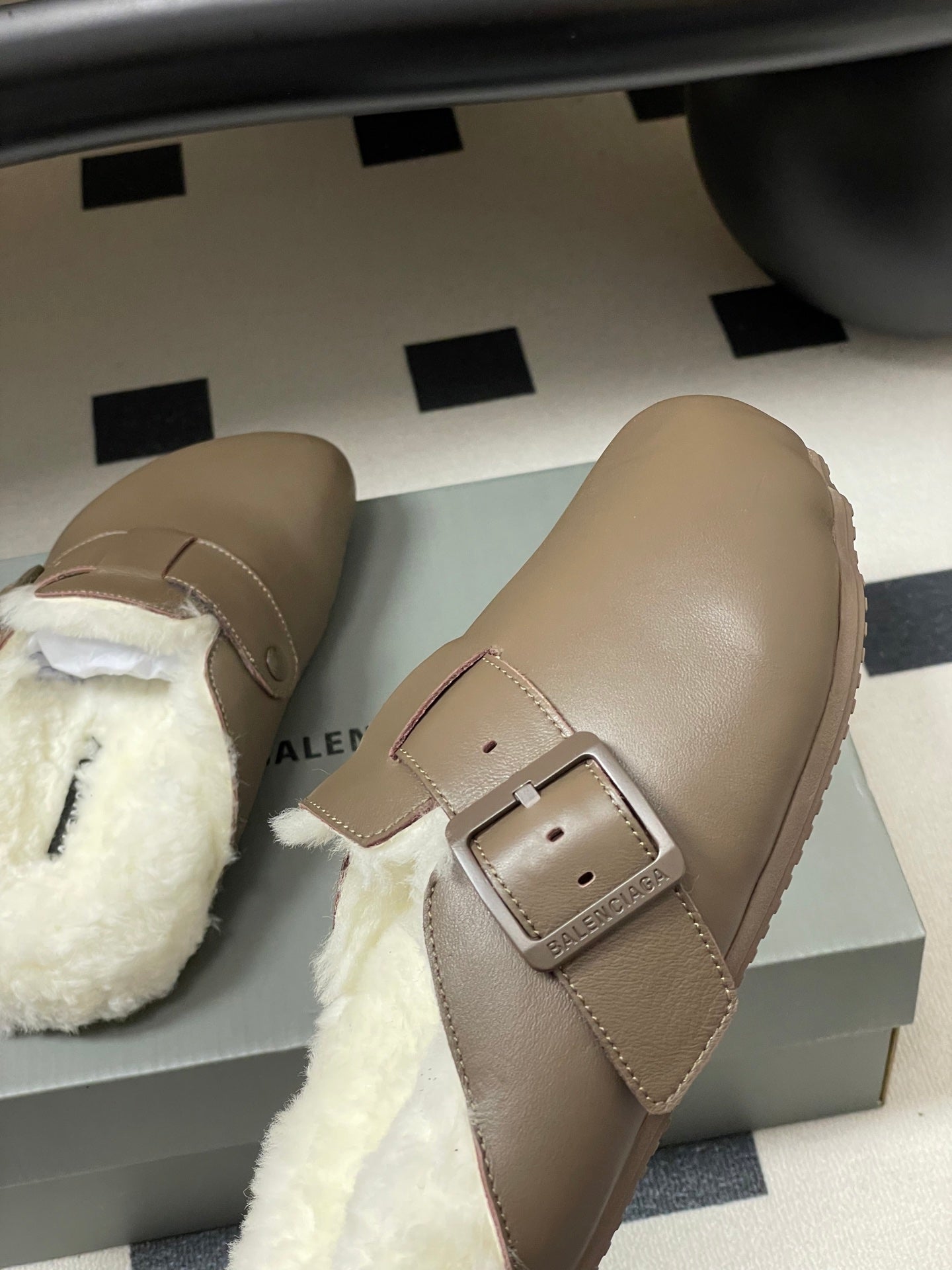 Taupe shearling sandals with adjustable buckle strap, side angle on box