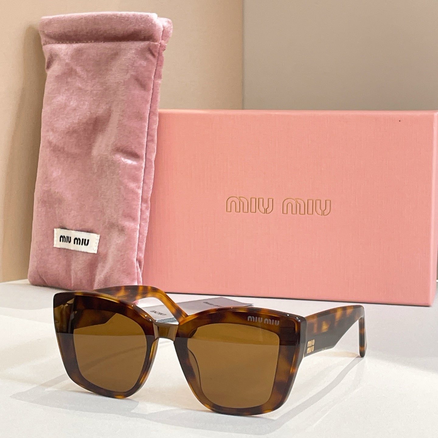 MiuMiu square sunglasses with tortoiseshell frames and amber lenses, in pink pouch