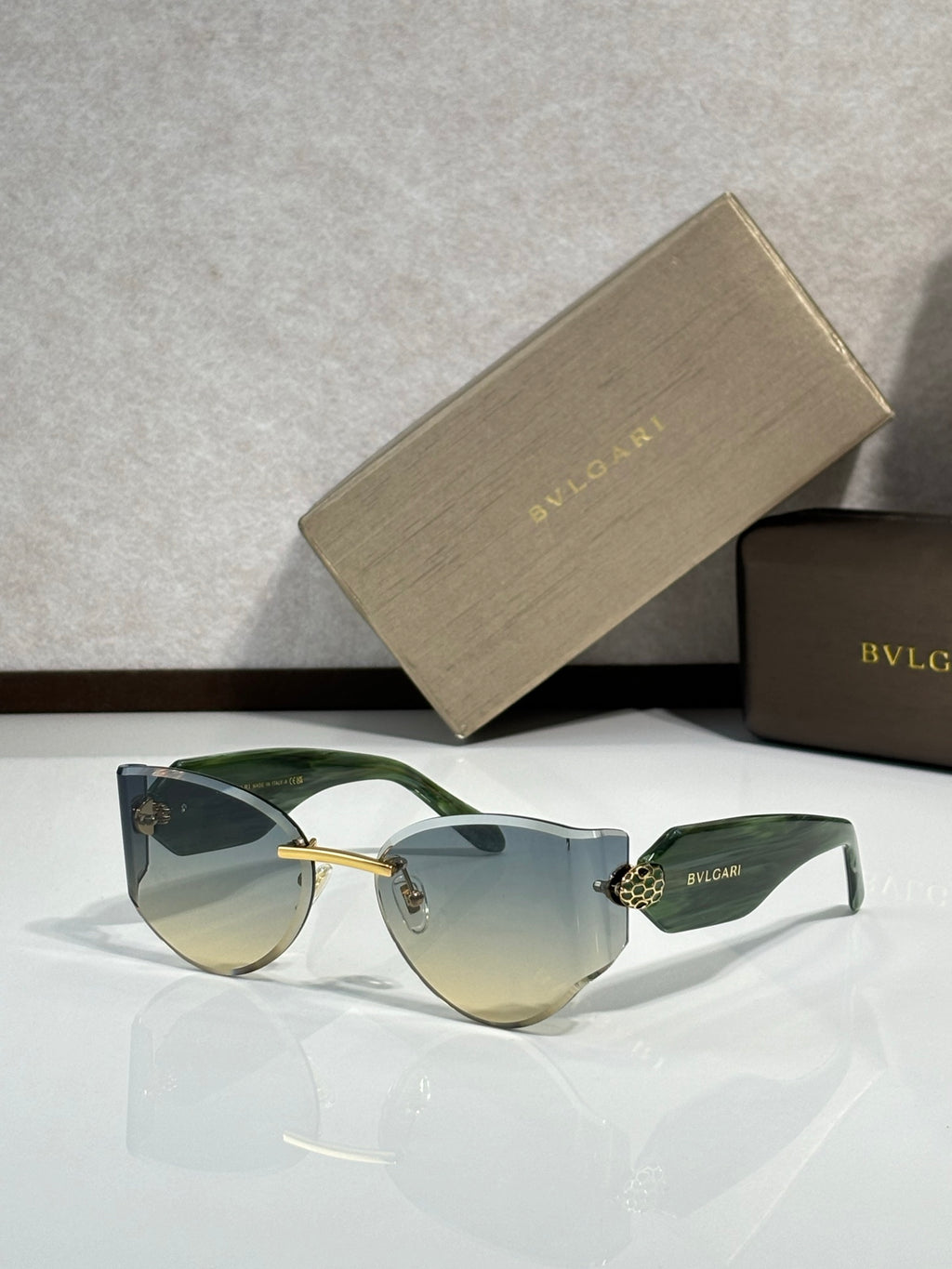 Cat-eye sunglasses by Bvlgari with green-tinted lenses and green frame with gold accents