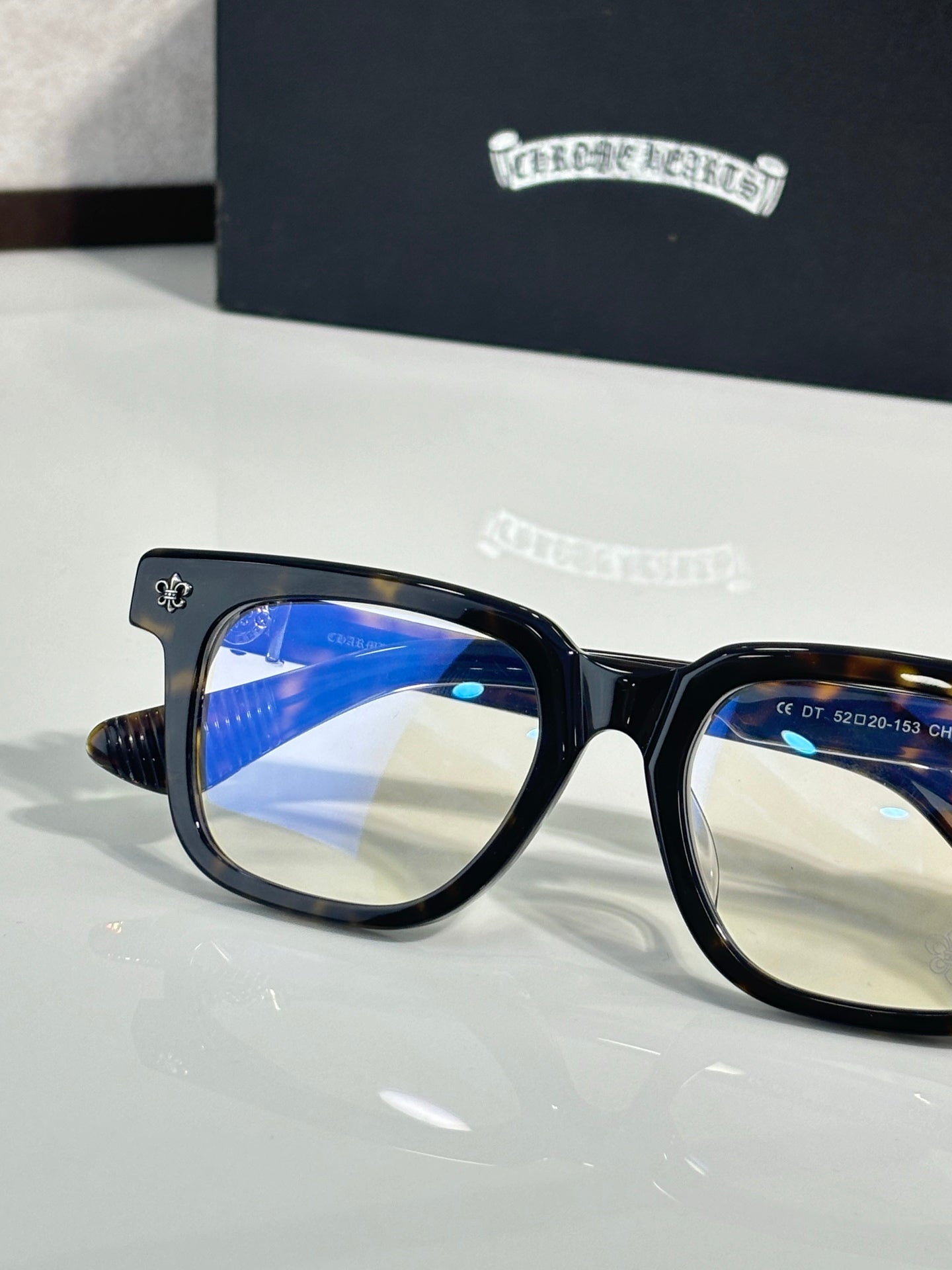 Black frame glasses with chrome temples and blue-tinted lenses