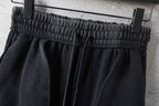 Black elastic waistband with gathered fabric above wide straight leg openings