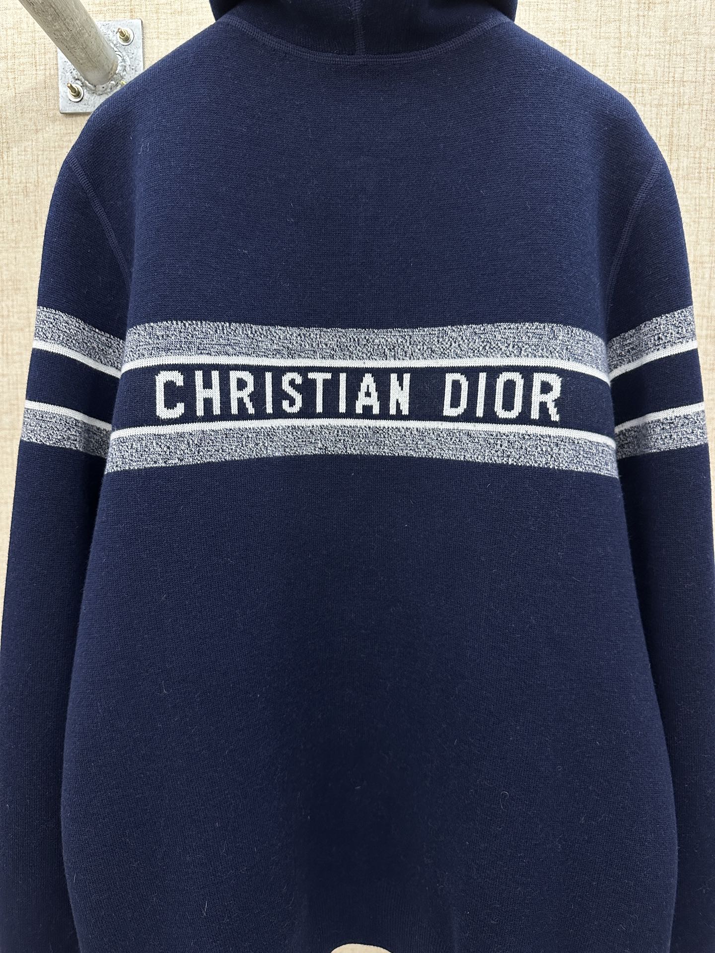 Navy zip-up hoodie close-up with hood and silver “CHRISTIAN DIOR” band