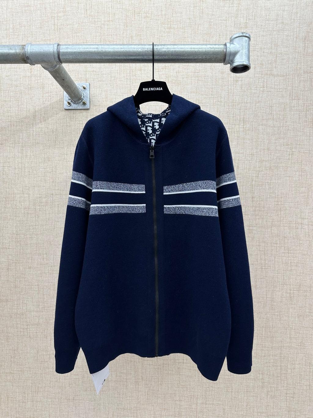Navy zip-up sweater with hood and silver-striped bands across sleeves