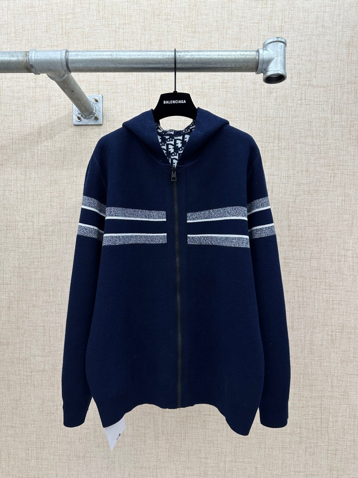 Navy zip-up sweater with hood and silver-striped bands across sleeves