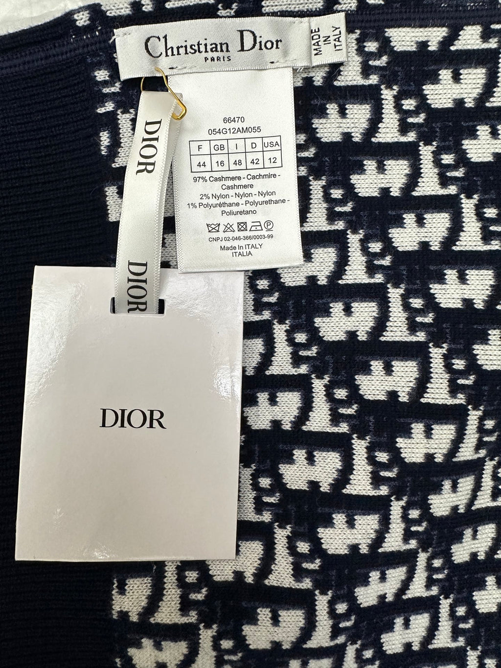Clothing label and tags attached to black-and-white patterned zip-up hoodie