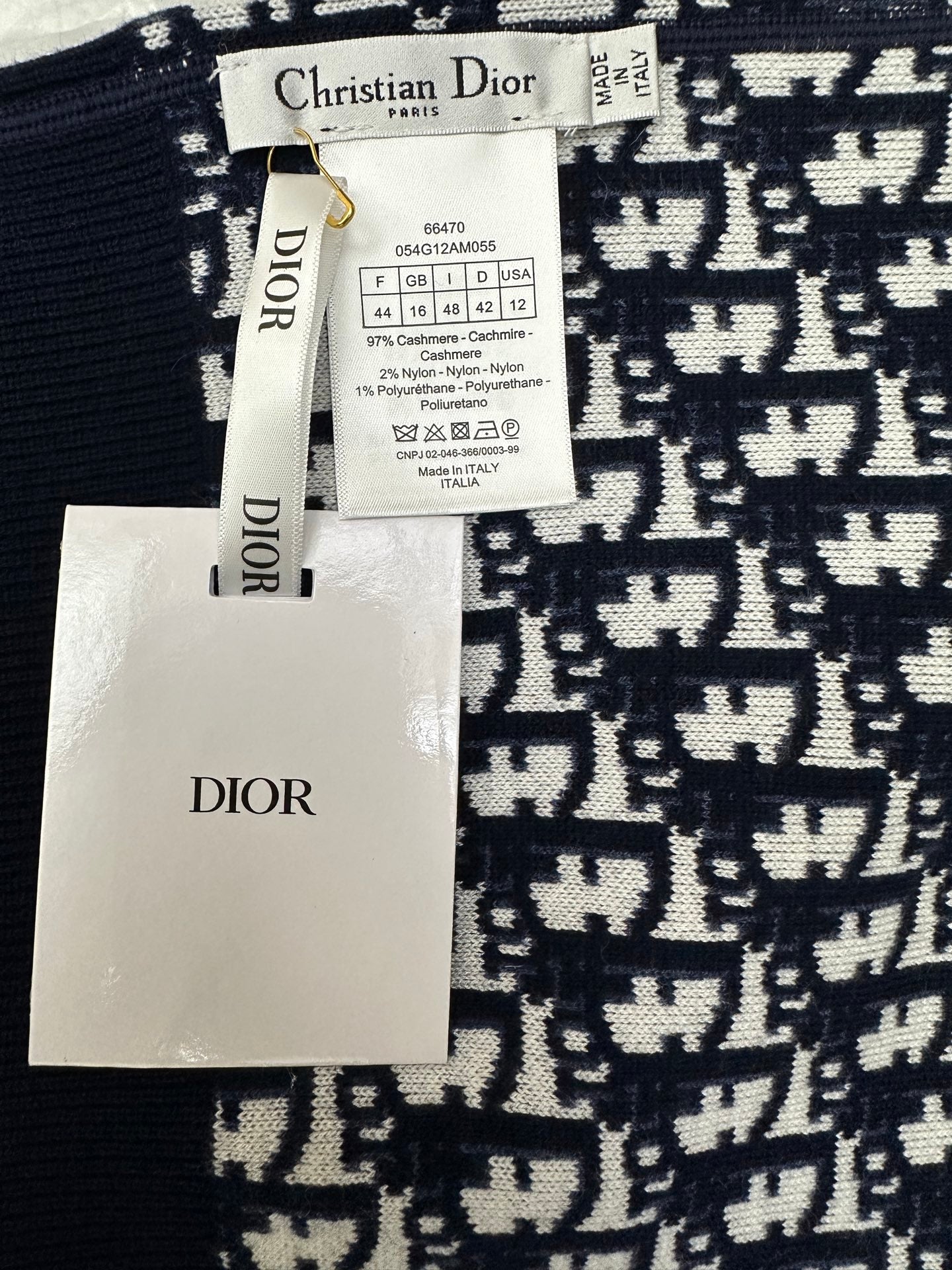 Brand tags and label on navy and white patterned zip-up hoodie fabric.