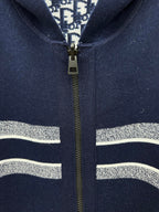 Navy zip-up hoodie close-up with gold zipper and silver-striped trim