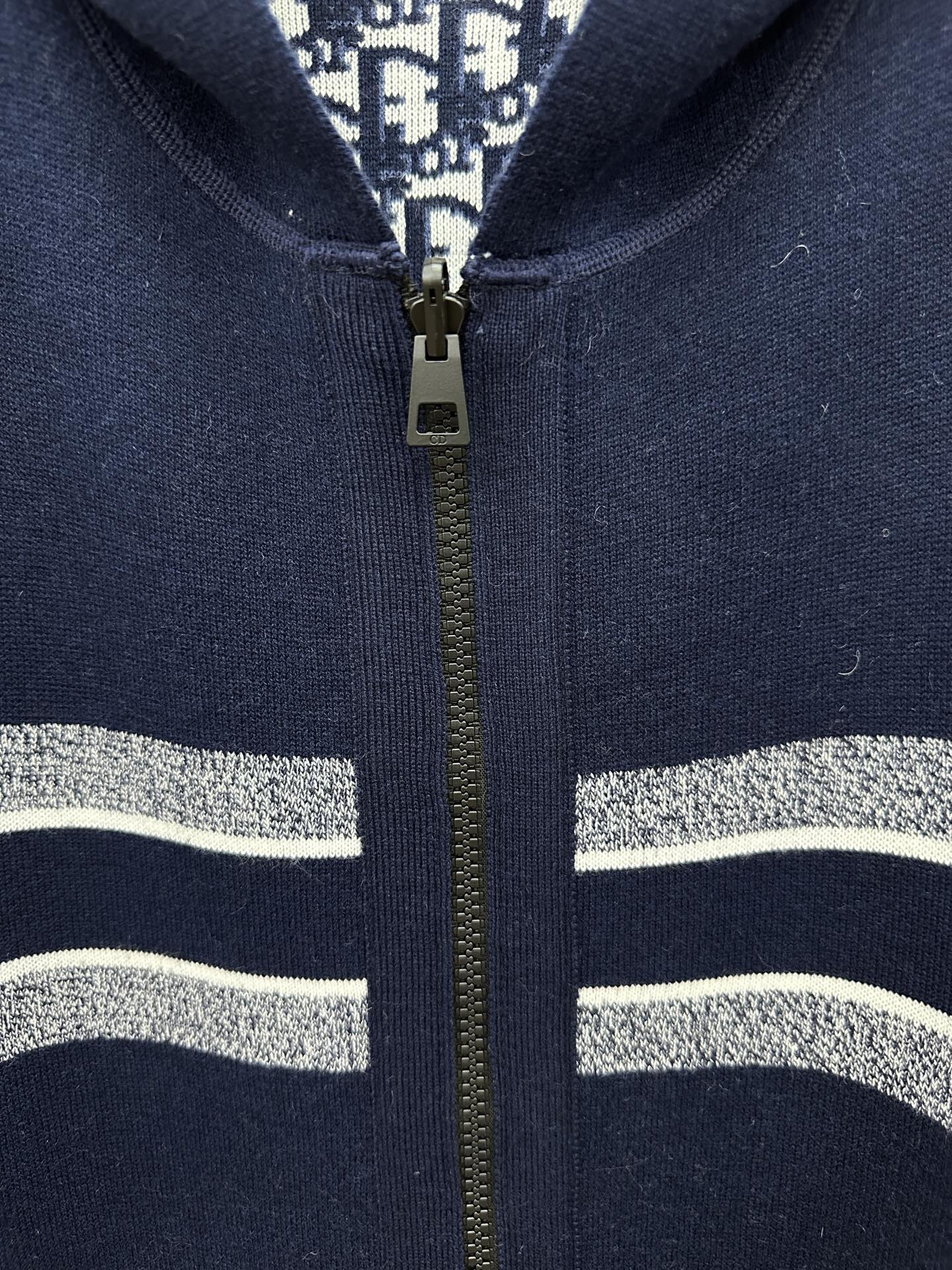 Navy zip-up hoodie close-up with gold zipper and silver-striped trim