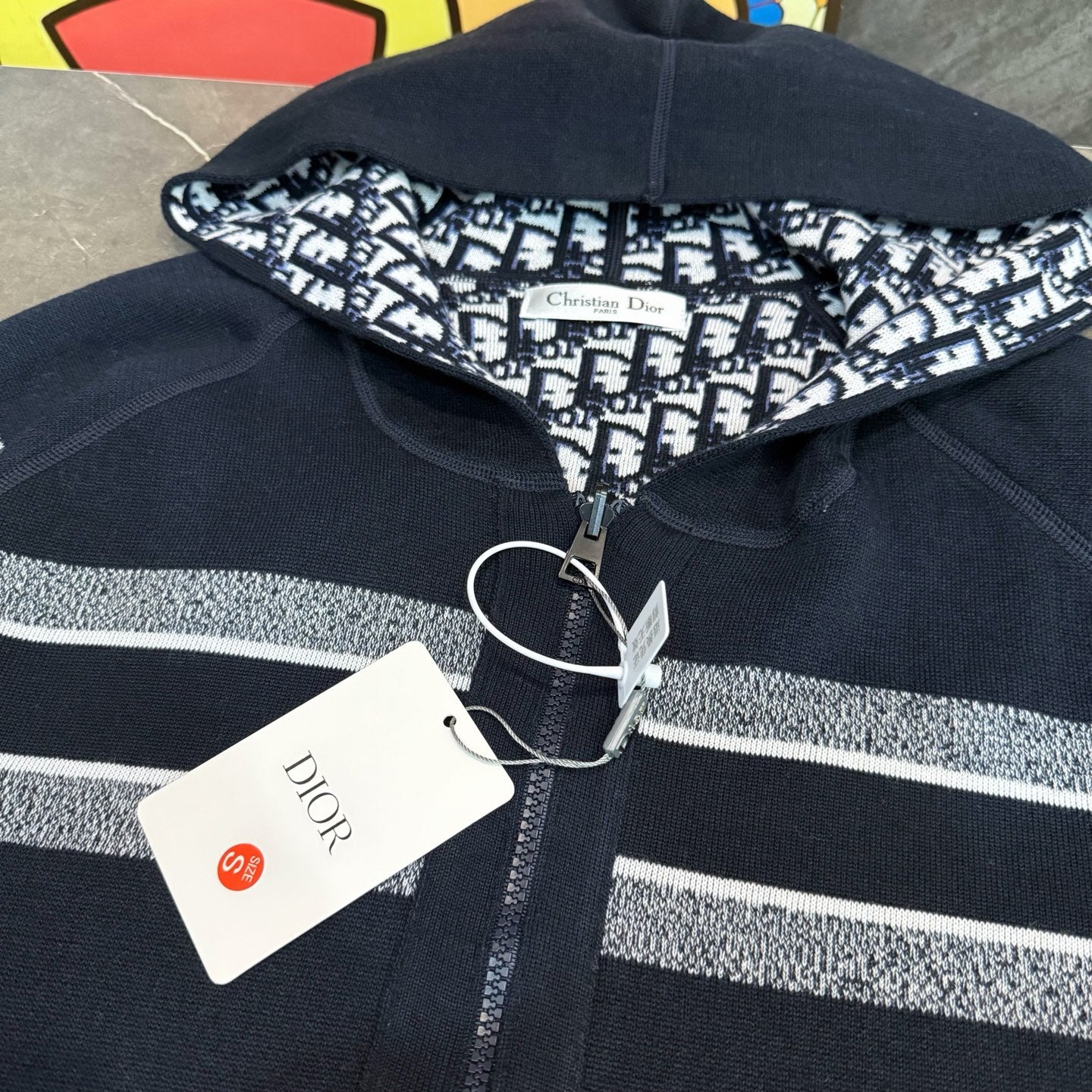 Navy zip hoodie with ribbed collar, silver logo stripe, and Dior price tag