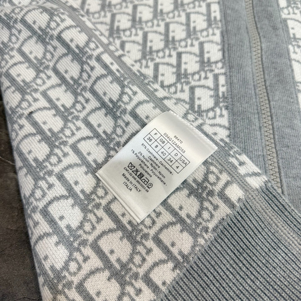 Close-up: gray and white monogram sweatshirt with care label sewn at seam.