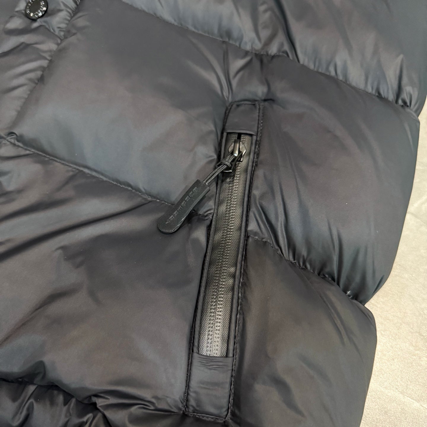 Dark puffer jacket with center zip and stitched quilted panels