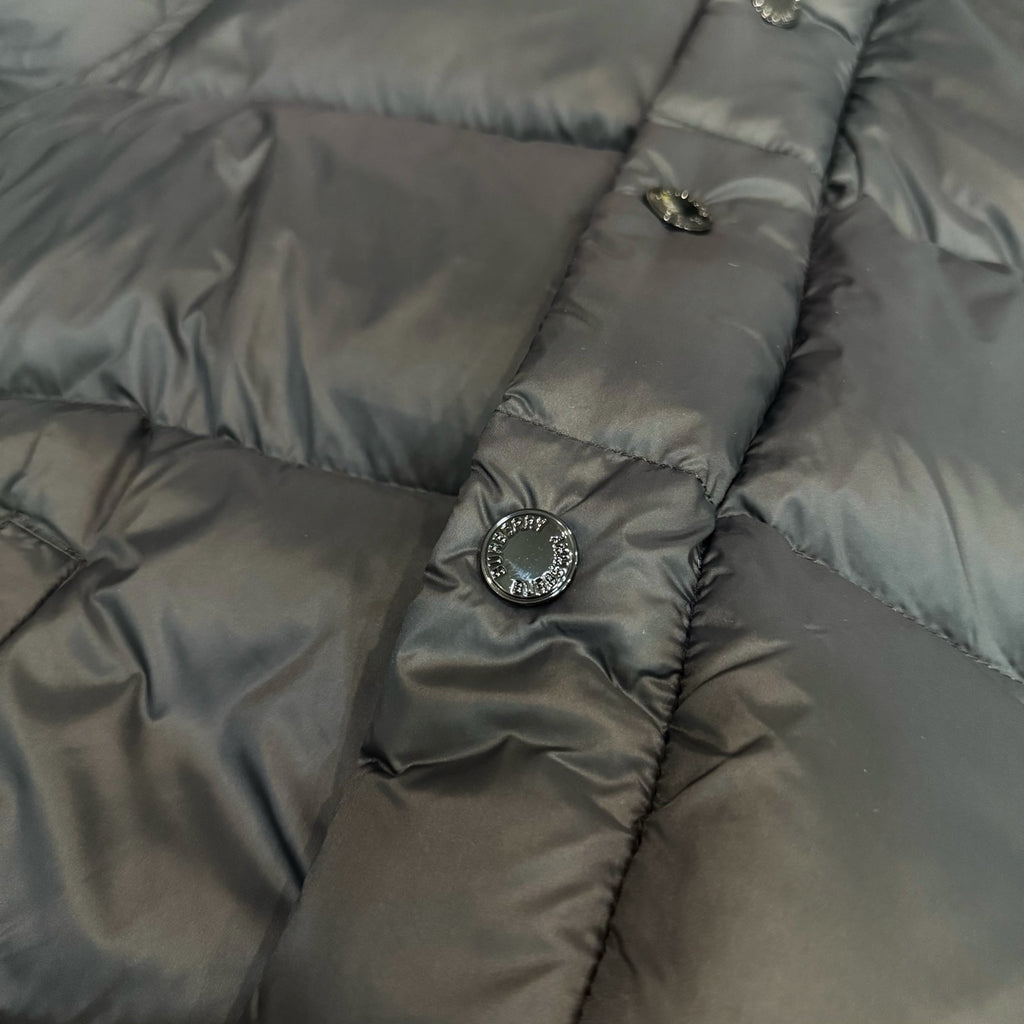 Dark puffer jacket panel with snap buttons and round emblem