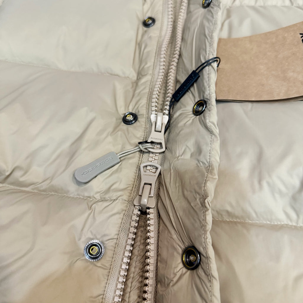 Burberry puffer jacket front, light beige with zip pull, snap buttons, and hardware.