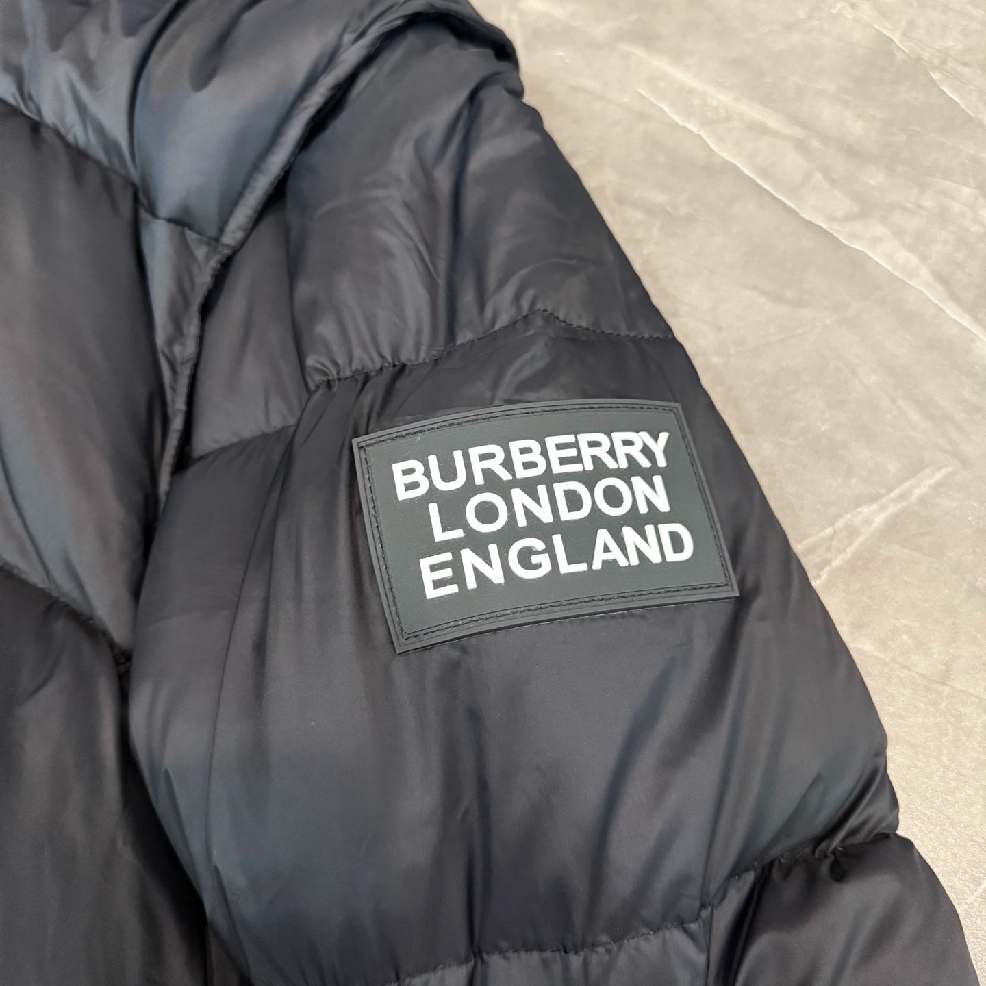 Dark puffer coat with 'BURBERRY LONDON ENGLAND' logo patch