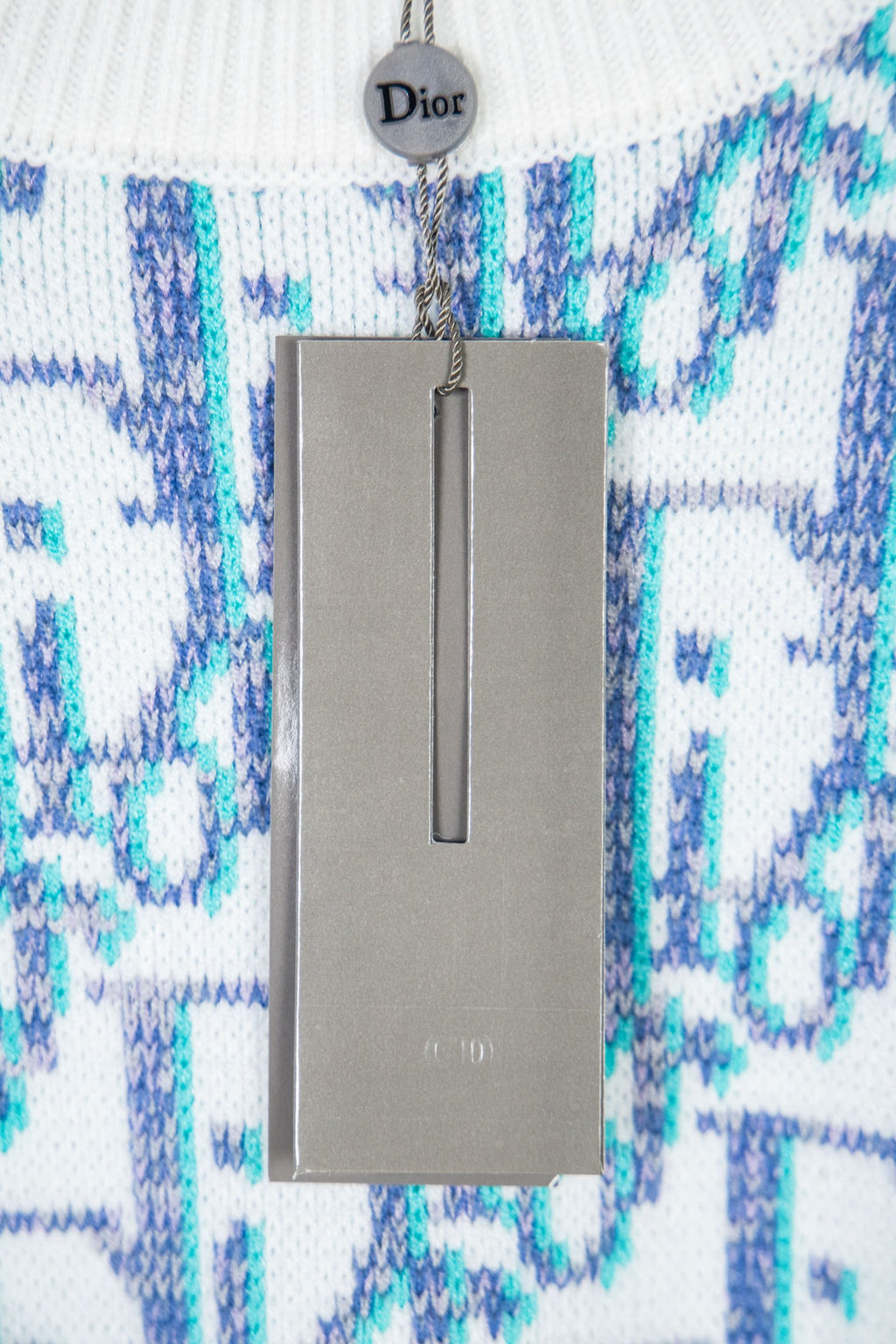 Dior knit sweater sleeve with blue logo pattern and gray product tag