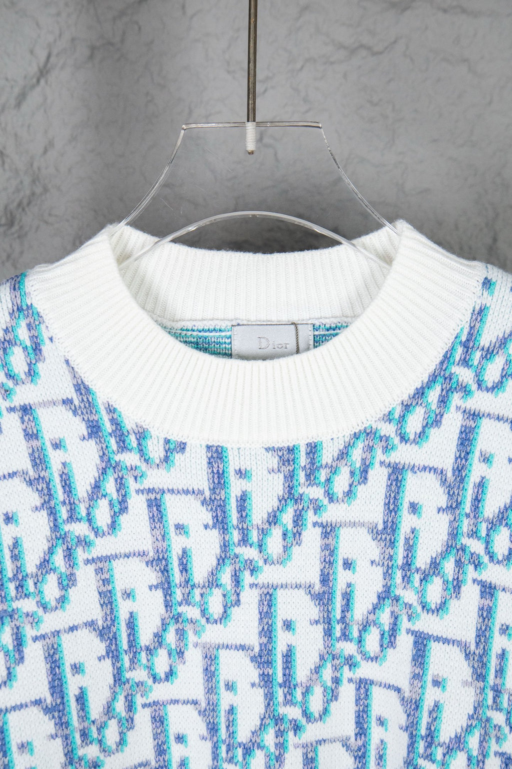 Dior knit sweater close-up: ribbed crew neck with blue and white logo pattern