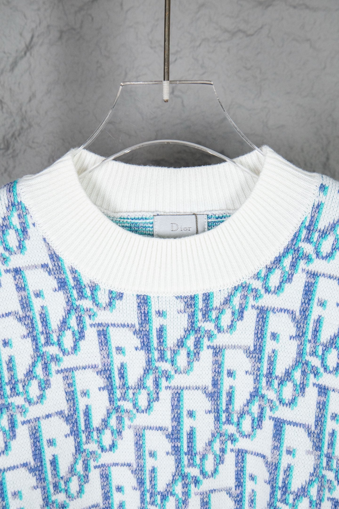 Dior knit sweater close-up: ribbed crew neck with blue and white logo pattern