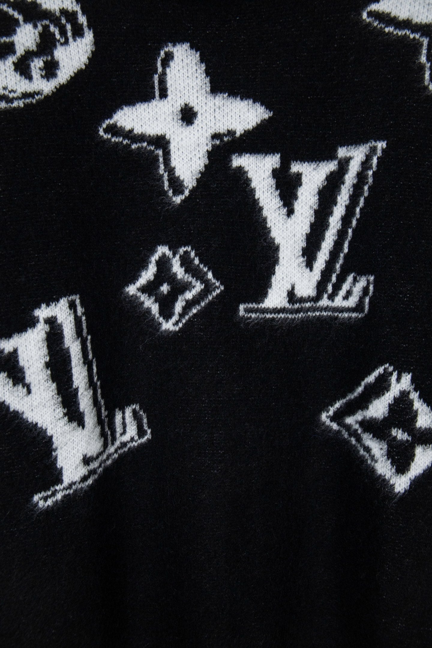 Louis Vuitton sweater close-up, black knit with white star and LV-style graphics