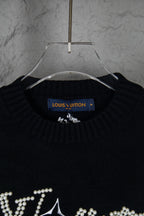 Black knit sweater neckline with blue Louis Vuitton label and rhinestone details