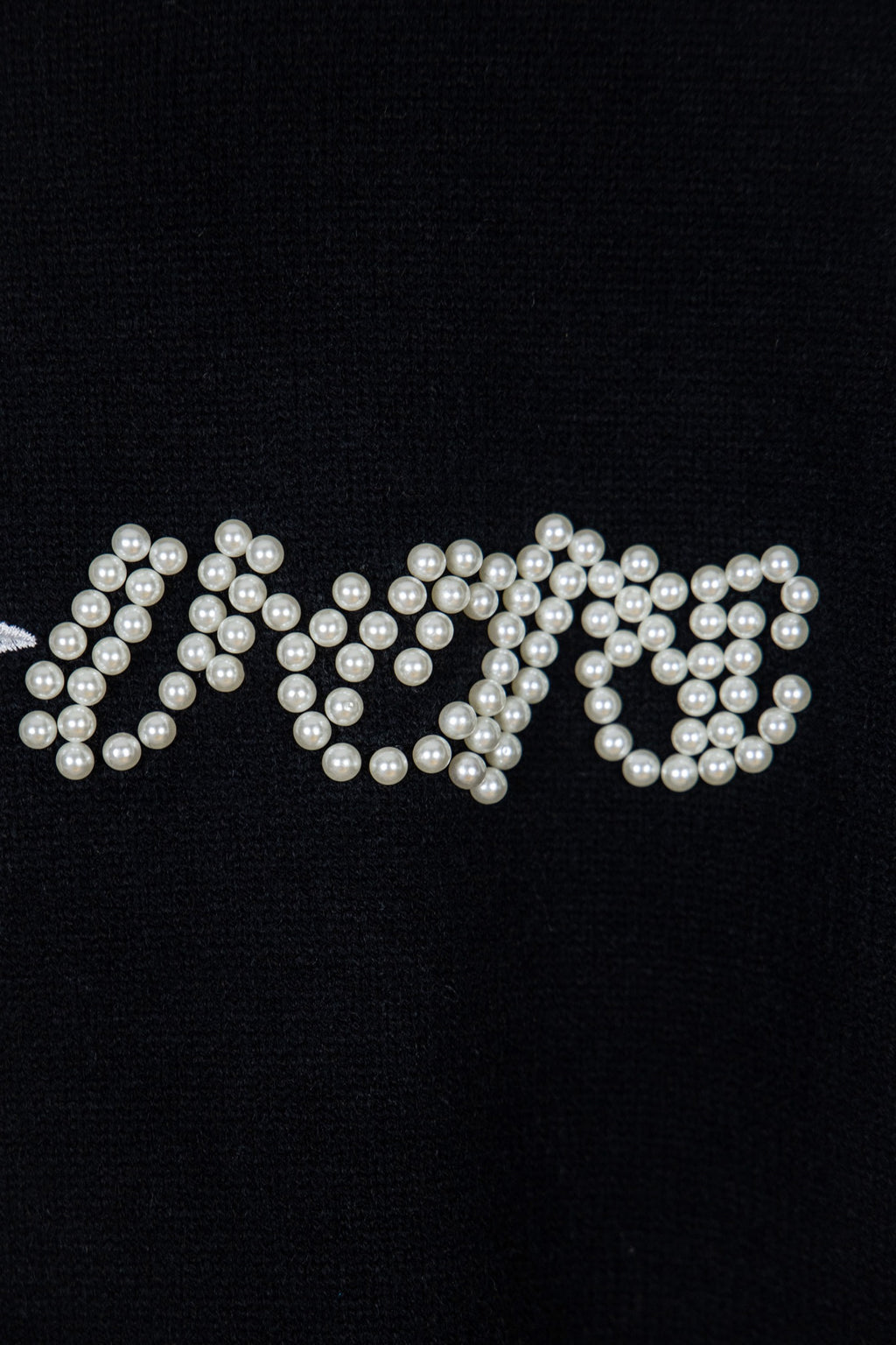 Black knit sweater with pearl-embellished lettering across the chest