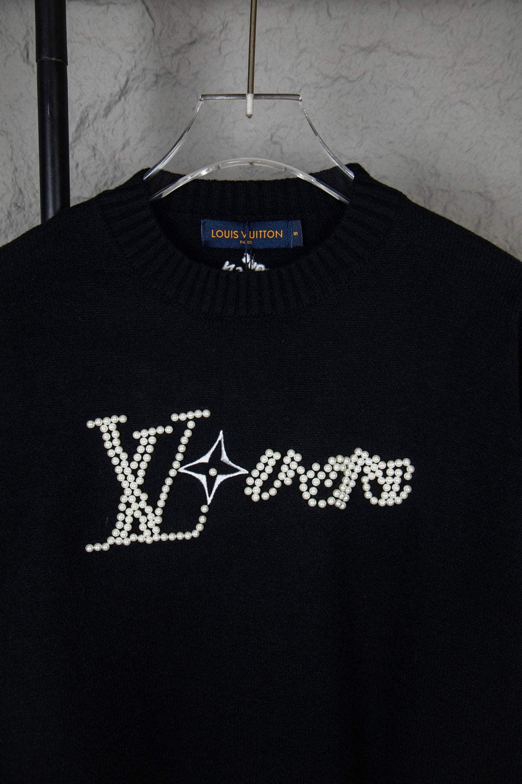 Black long-sleeve knit sweater close-up with rhinestone LV-style chest lettering