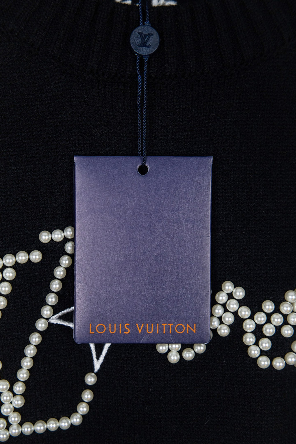 Black knit sweater with hanging Louis Vuitton tag and pearl logo details