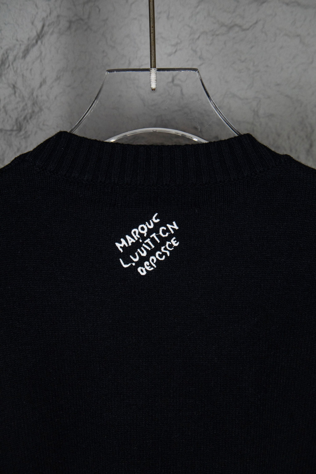 Black long-sleeve knit sweater with small white graphic text near collar