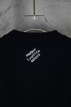 Black long-sleeve knit sweater with small white graphic text near collar