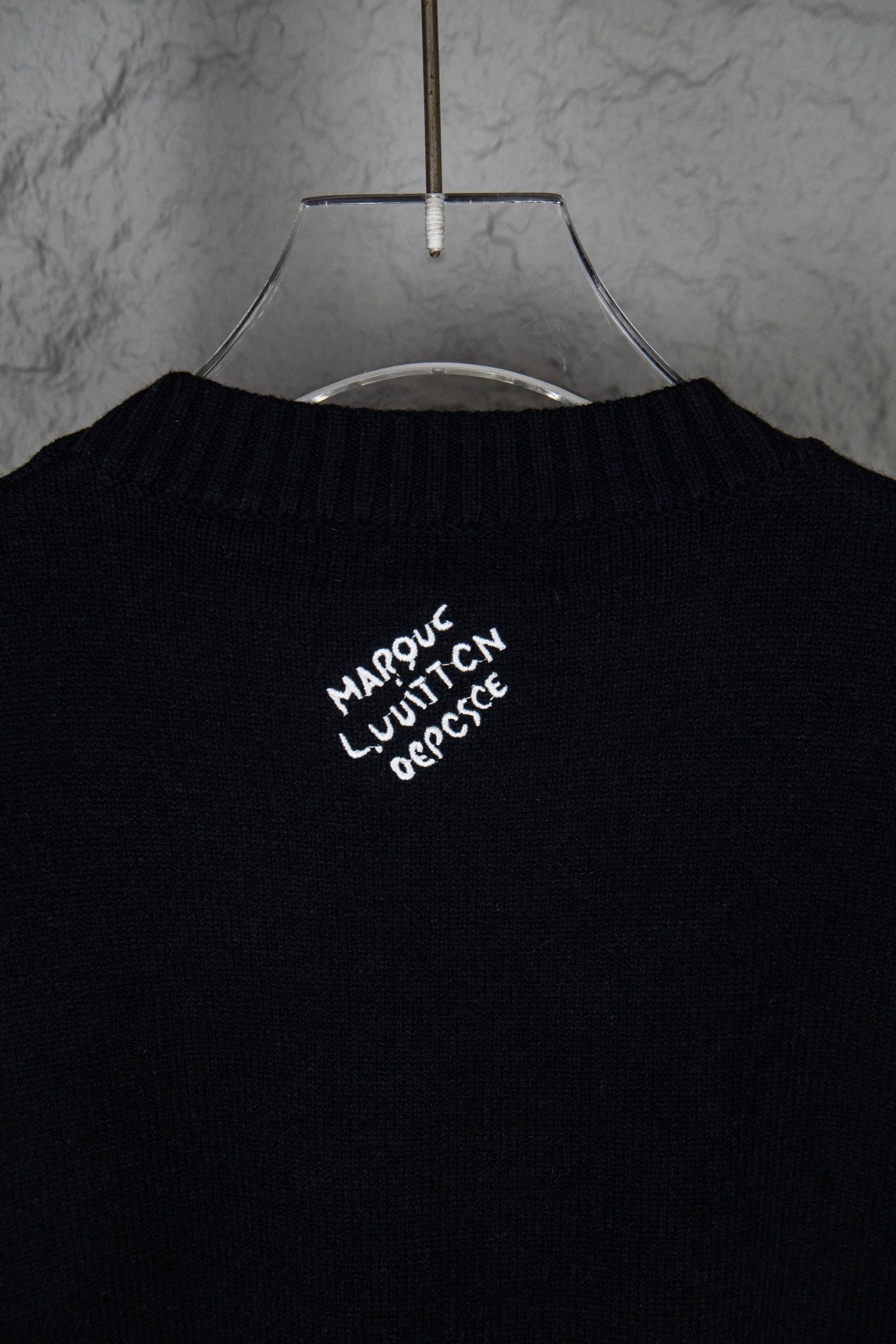 Black long-sleeve knit sweater with small white graphic text near collar