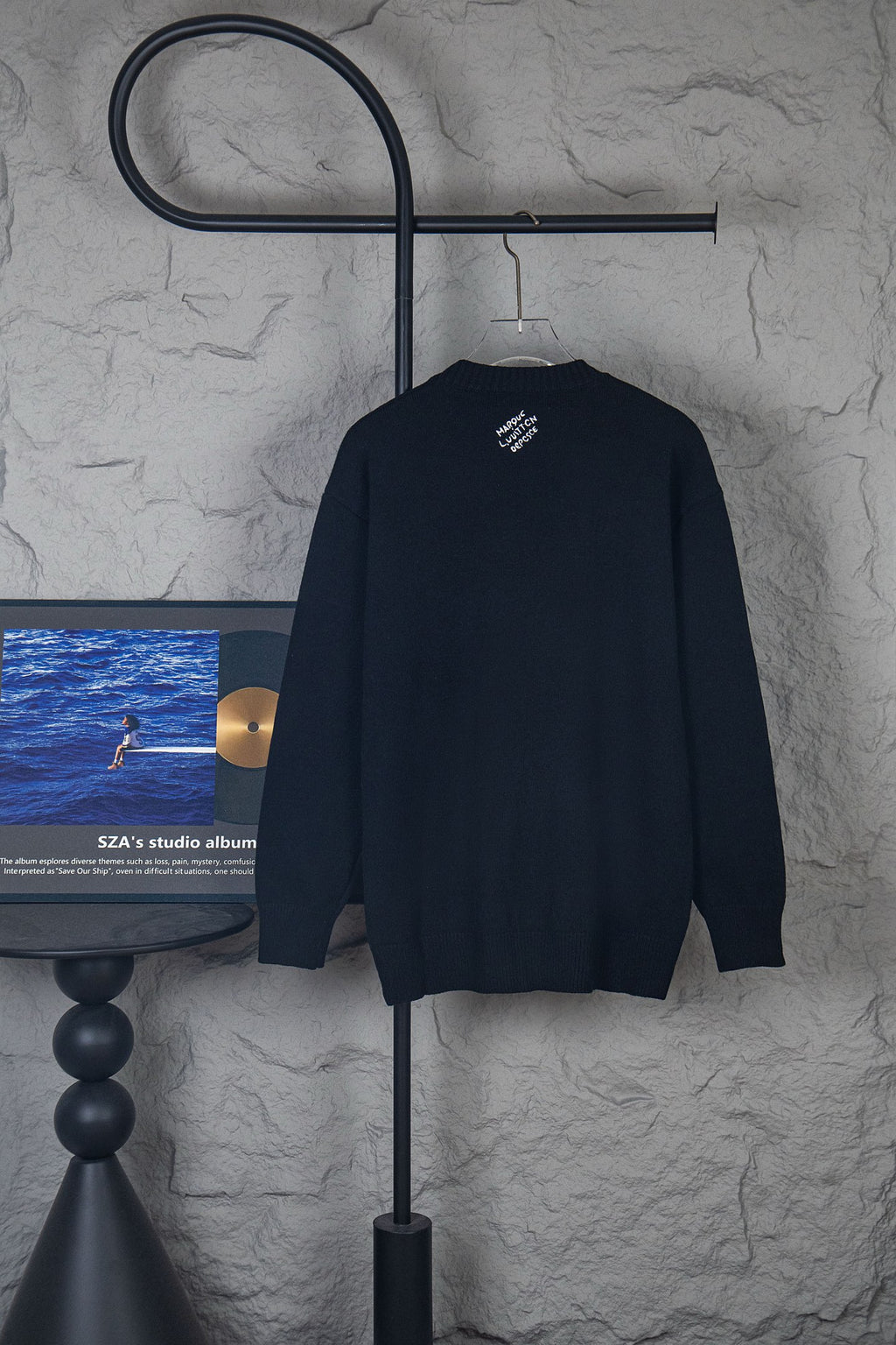 Dark long-sleeve knit sweater with small center logo on back