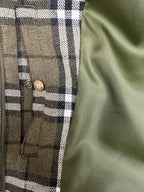 Olive green plaid jacket front with two brass snap buttons and vertical pocket seams