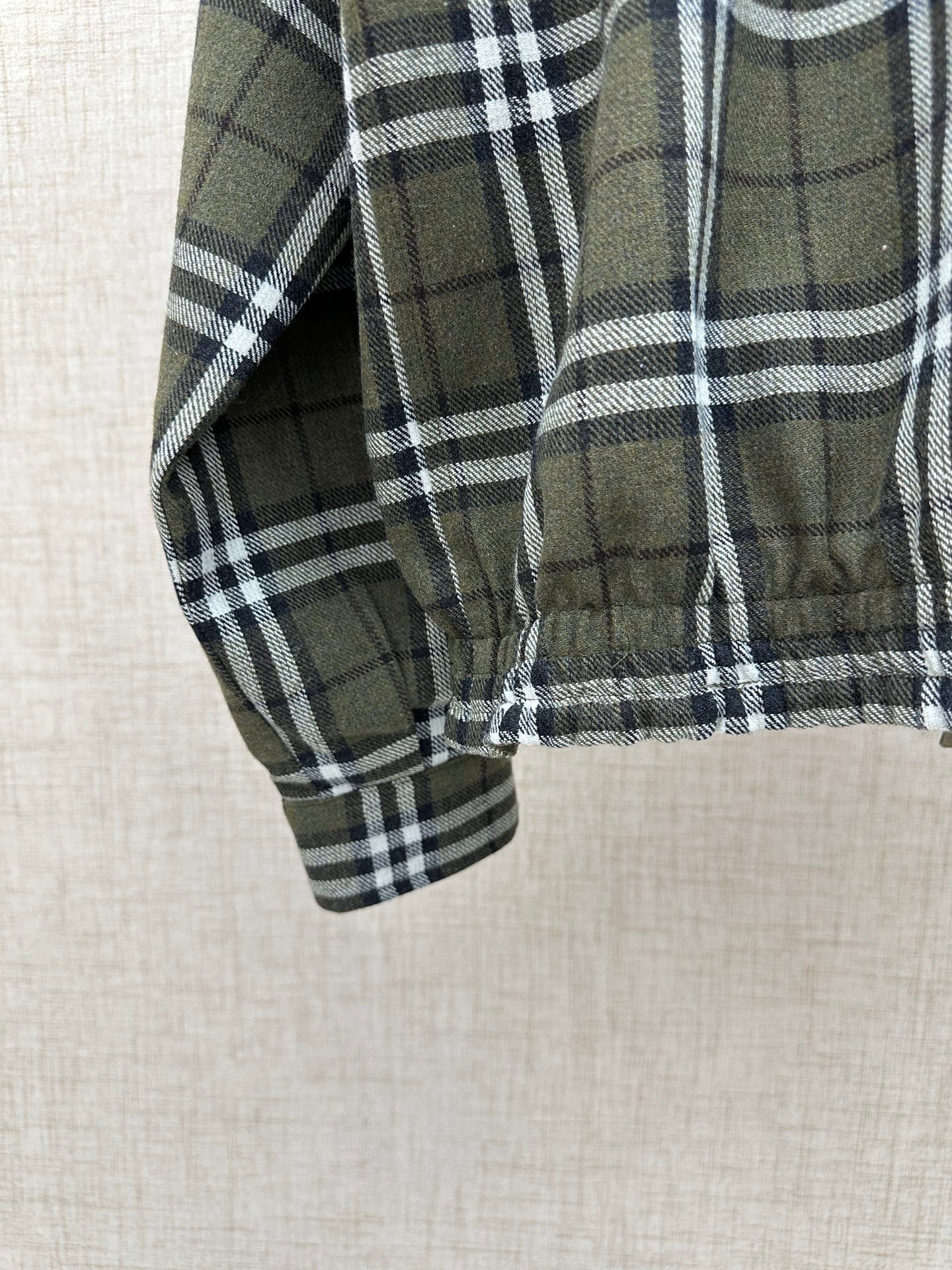 Olive green plaid jacket sleeve with elastic cuff and stitched hem edge