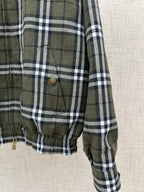 Olive green and black plaid jacket front pocket with brass button and drawstring hem