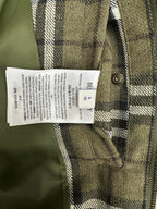 Olive green plaid jacket care label on inner seam near metal button