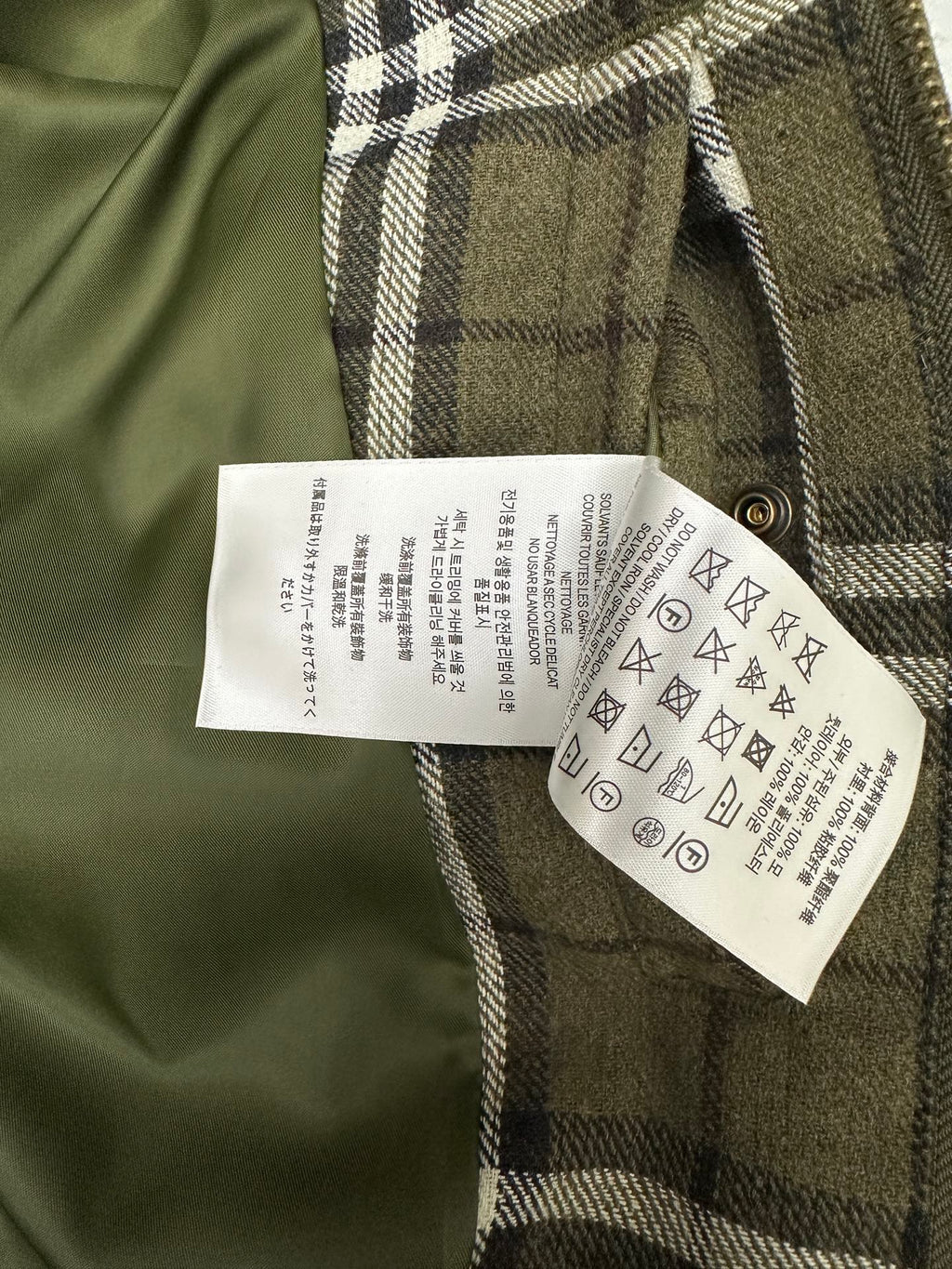 Olive green plaid jacket with white care label on inner side
