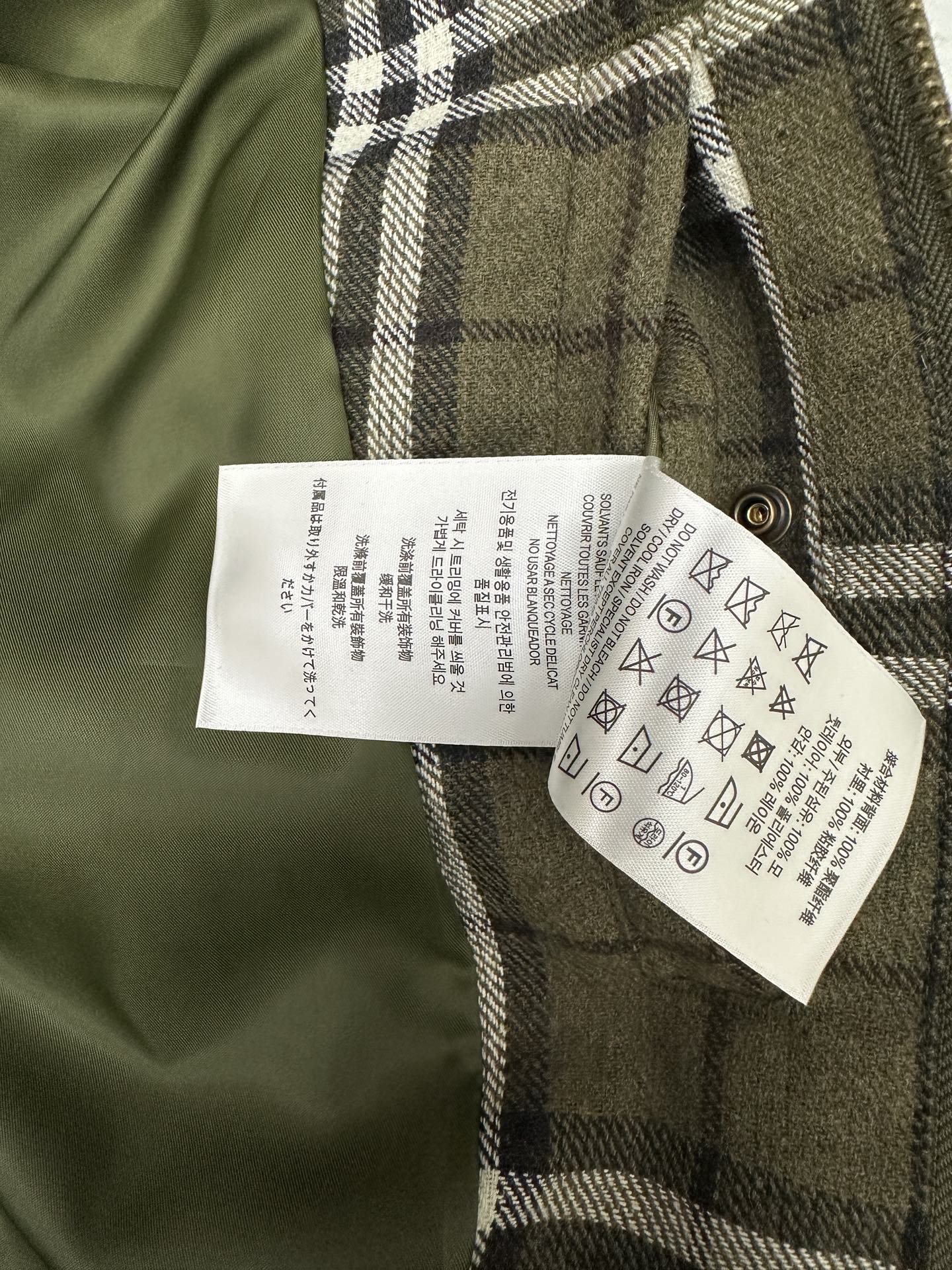 Olive green plaid jacket with white care label on inner side