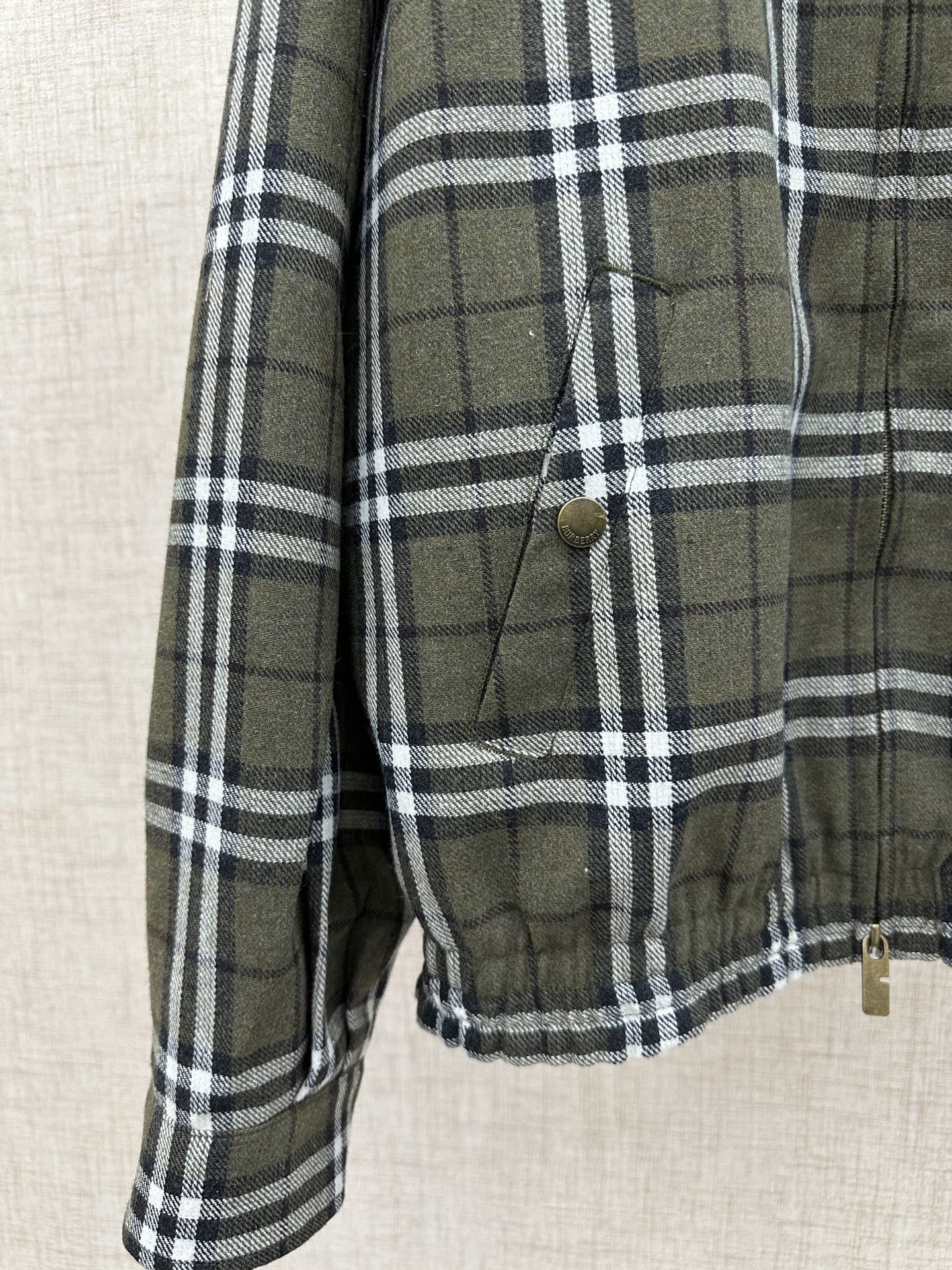 Olive green and black plaid jacket sleeve with cuff and stitched front pocket detail