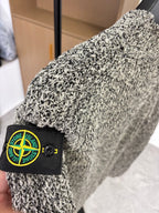 Grey speckled jacket sleeve with Stone Island black logo patch and button