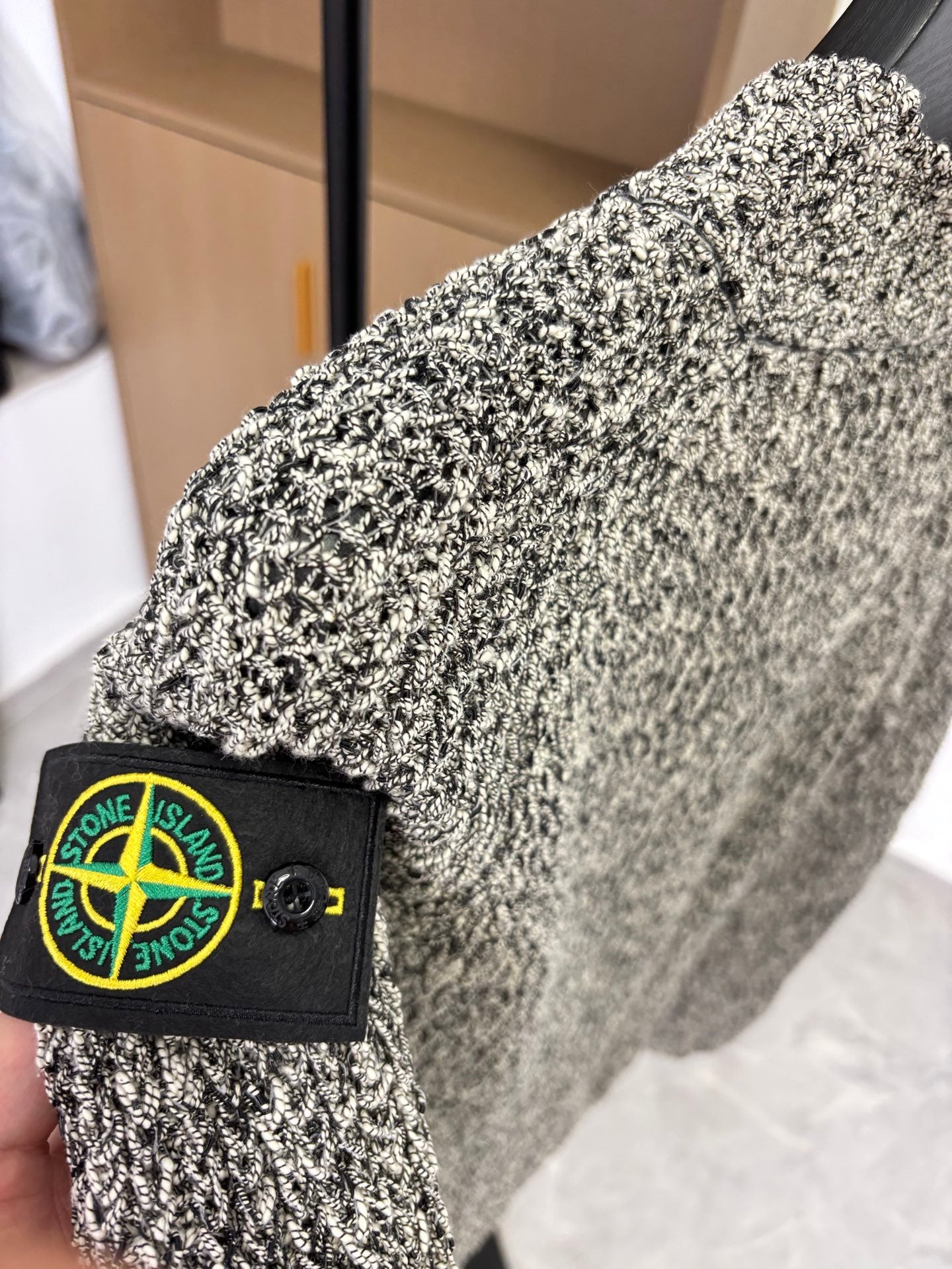Grey speckled jacket sleeve with Stone Island black logo patch and button
