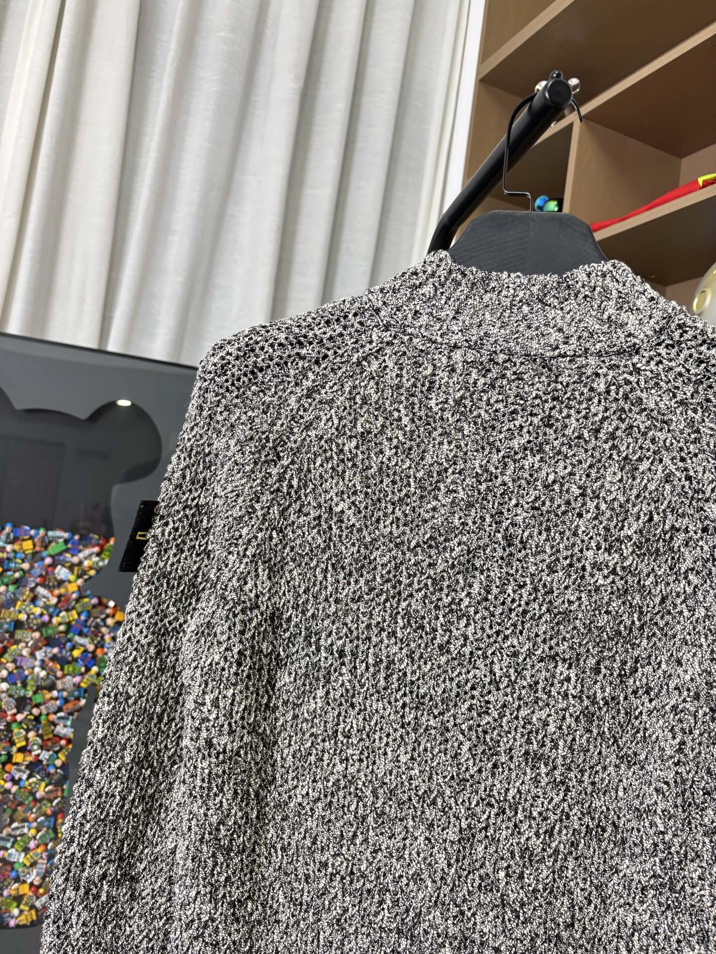 Textured black-and-white speckled jacket back view on hanger