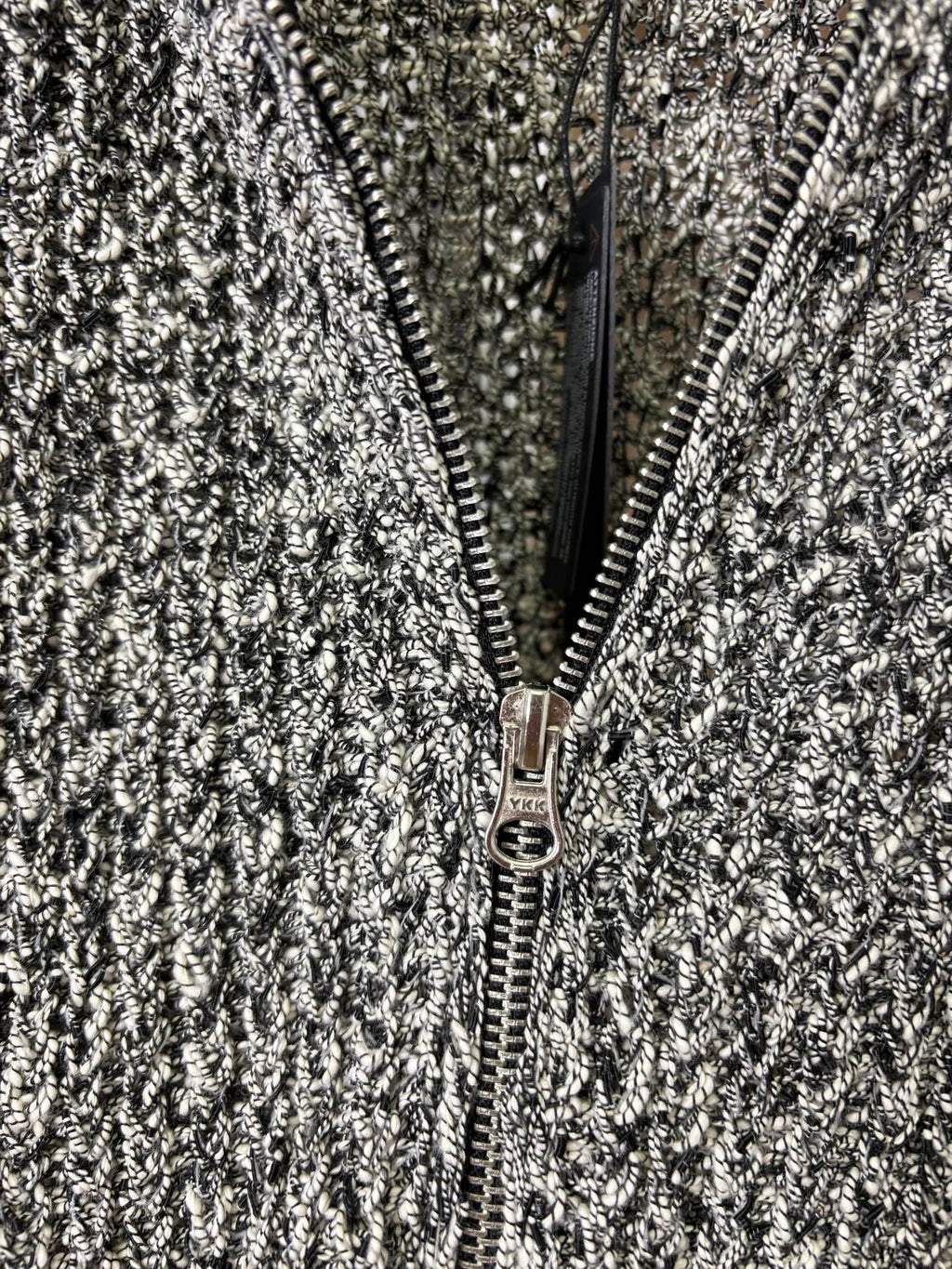 Close-up of front zipper on black-and-white speckled textured jacket