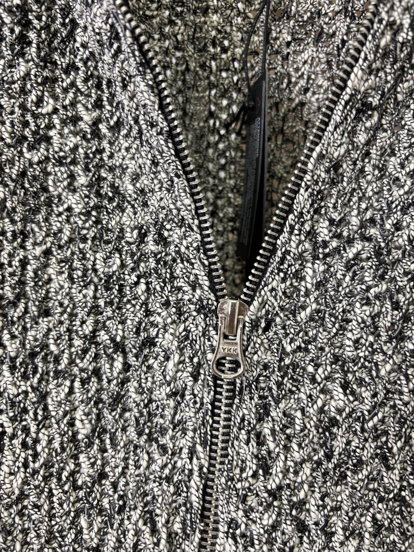 Close-up of front zipper on black-and-white speckled textured jacket