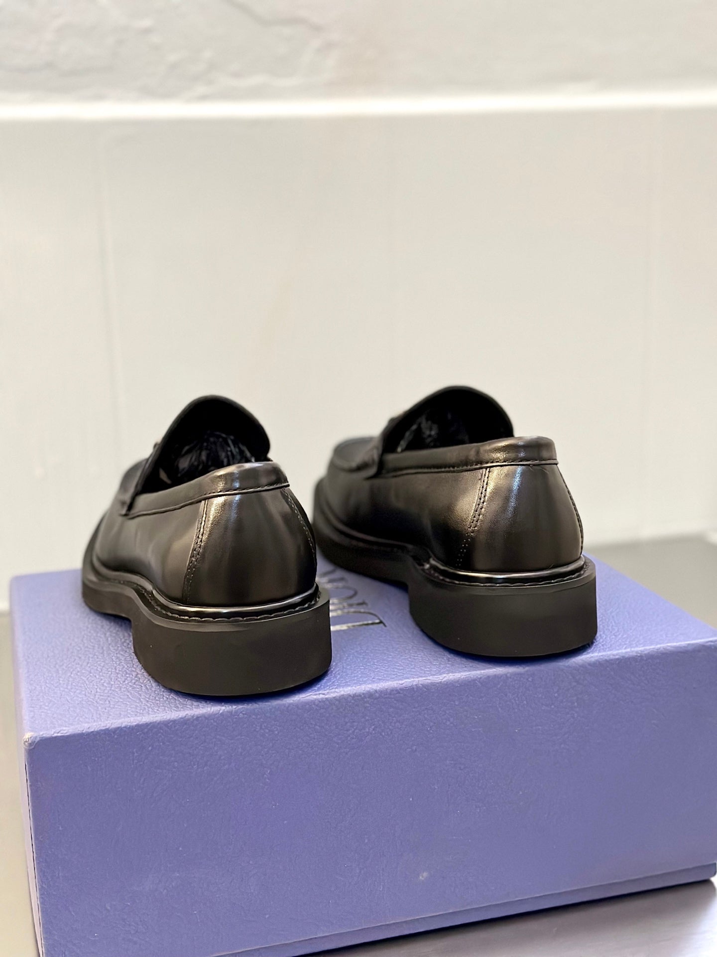 Back view of dark leather Dior loafers with low stacked heel and rounded toe
