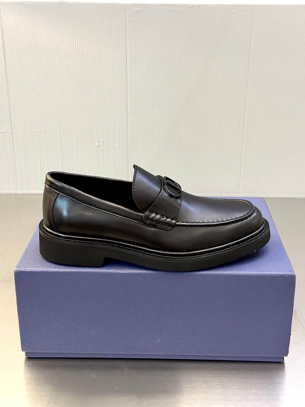 Side view of dark leather Dior loafers with D buckle and low platform sole