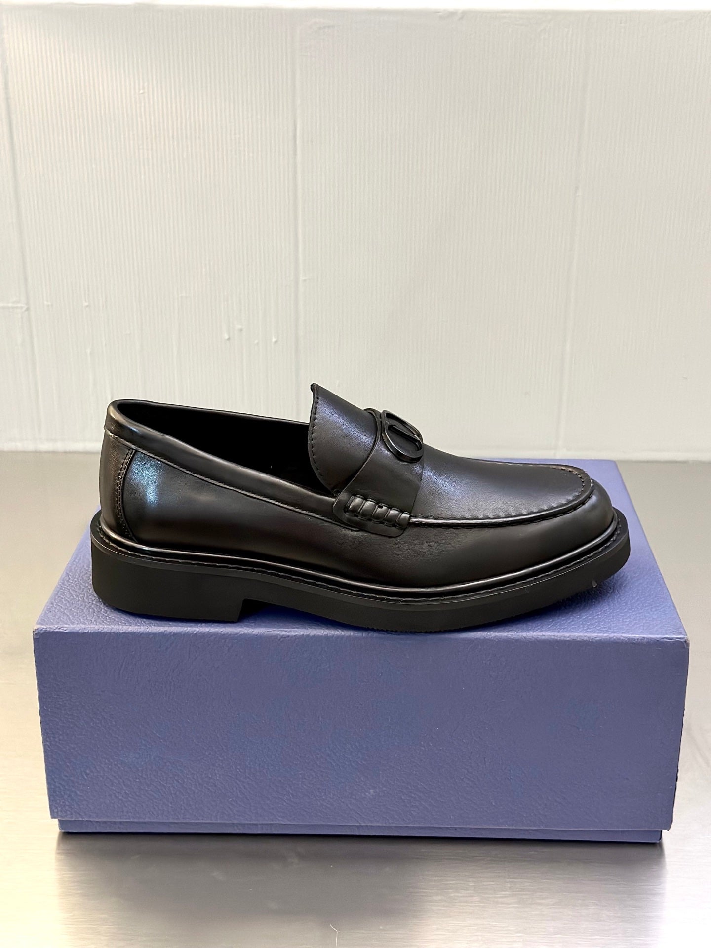 Side view of dark leather Dior loafers with D buckle and low platform sole