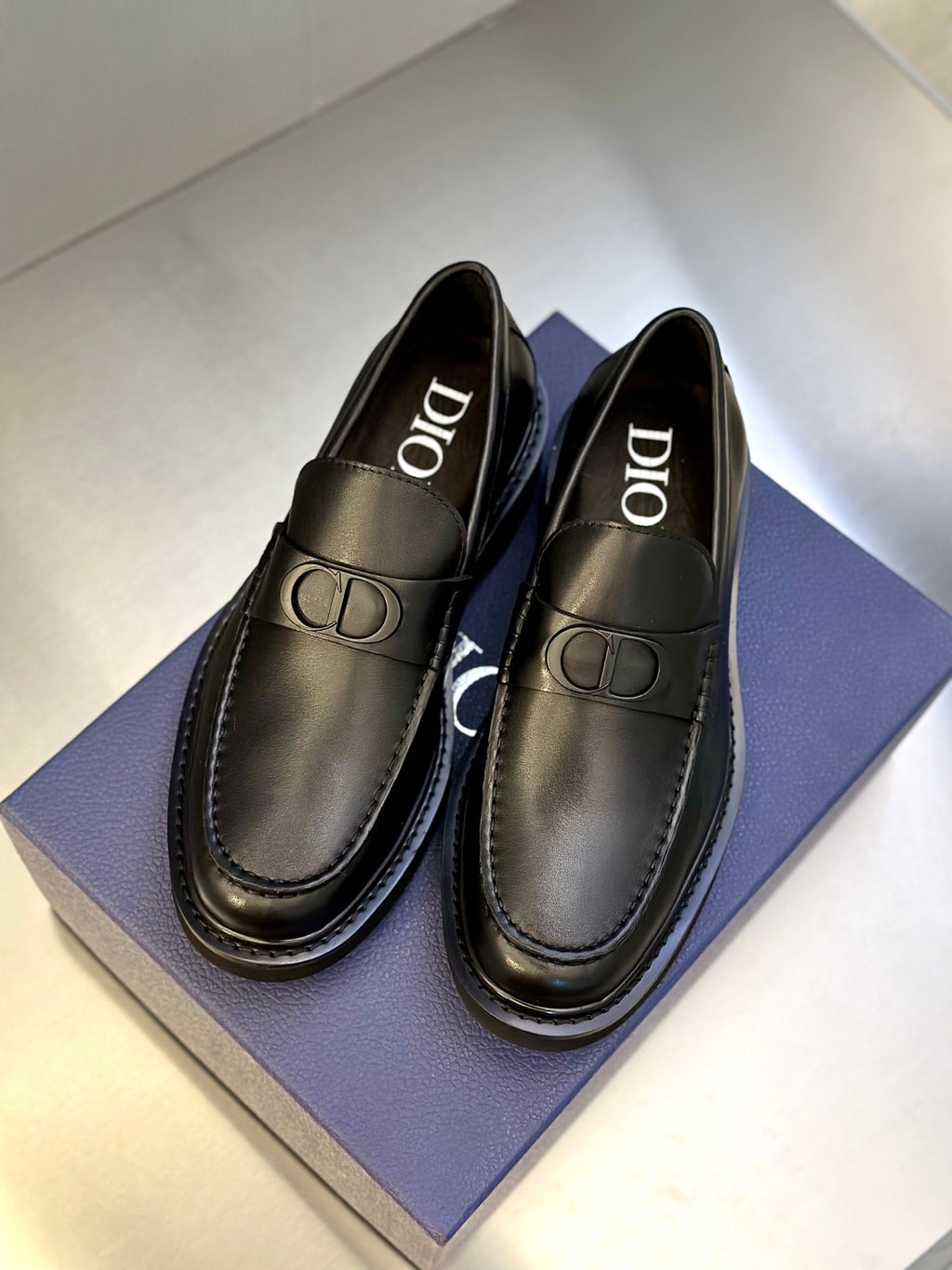 Pair of dark leather Dior loafers with gold-tone D buckle detail and stitched edges