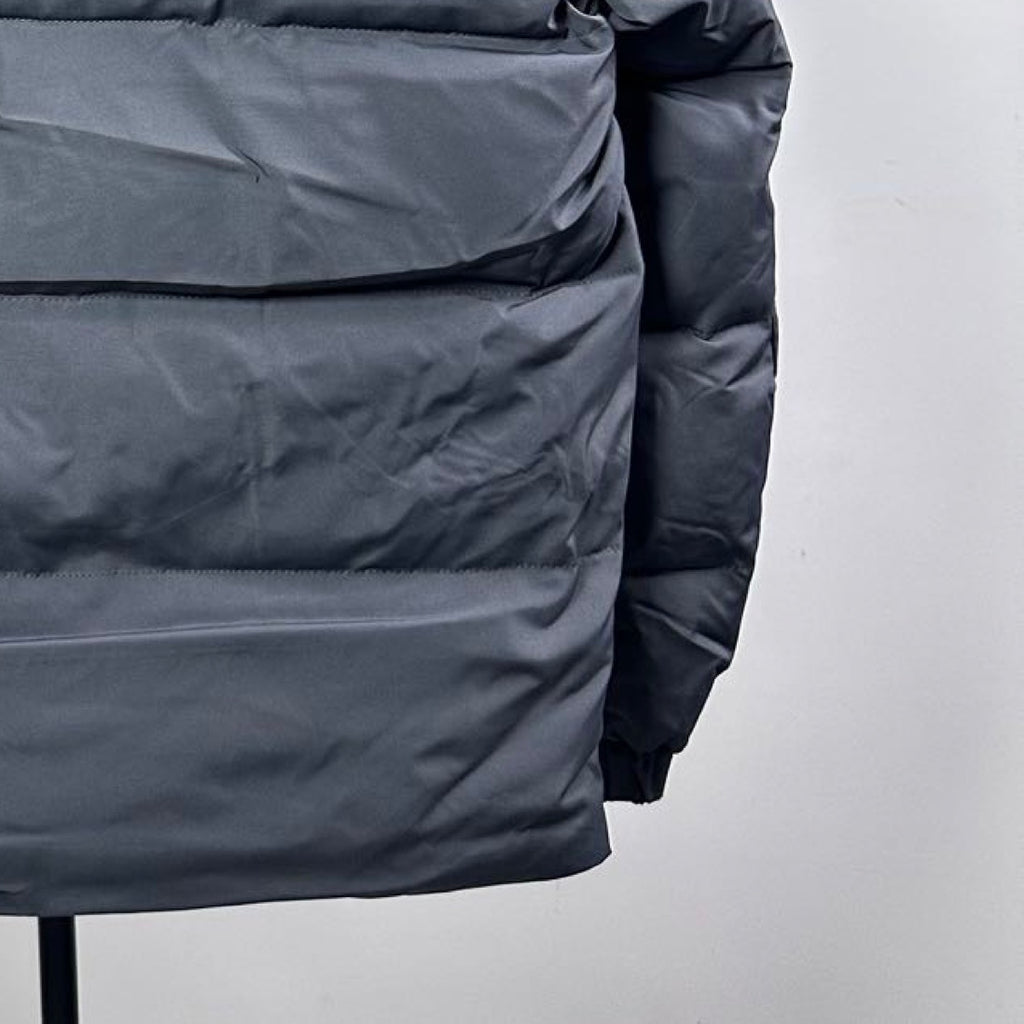 Dark gray long puffer jacket, padded front panel close-up with stitching details
