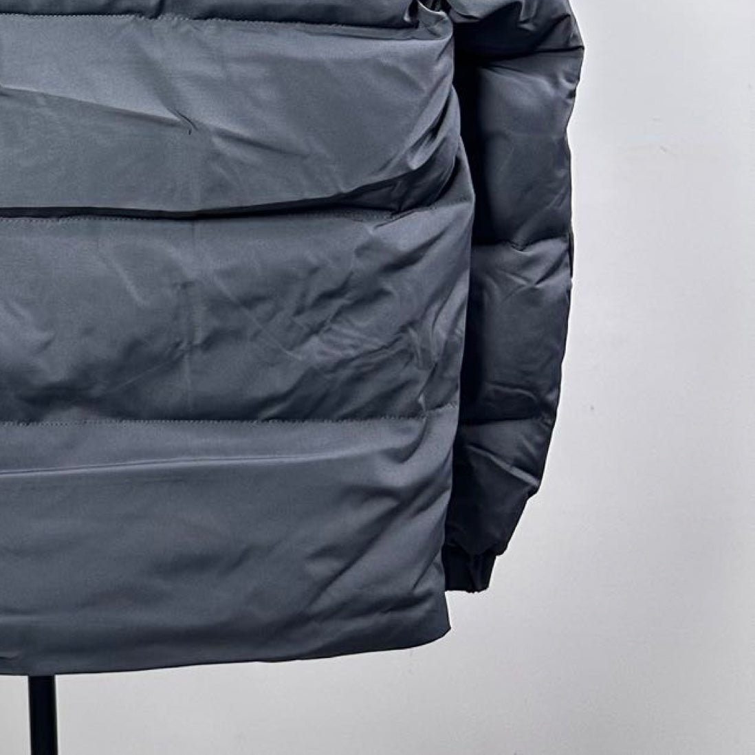 Dark gray long puffer jacket, padded front panel close-up with stitching details