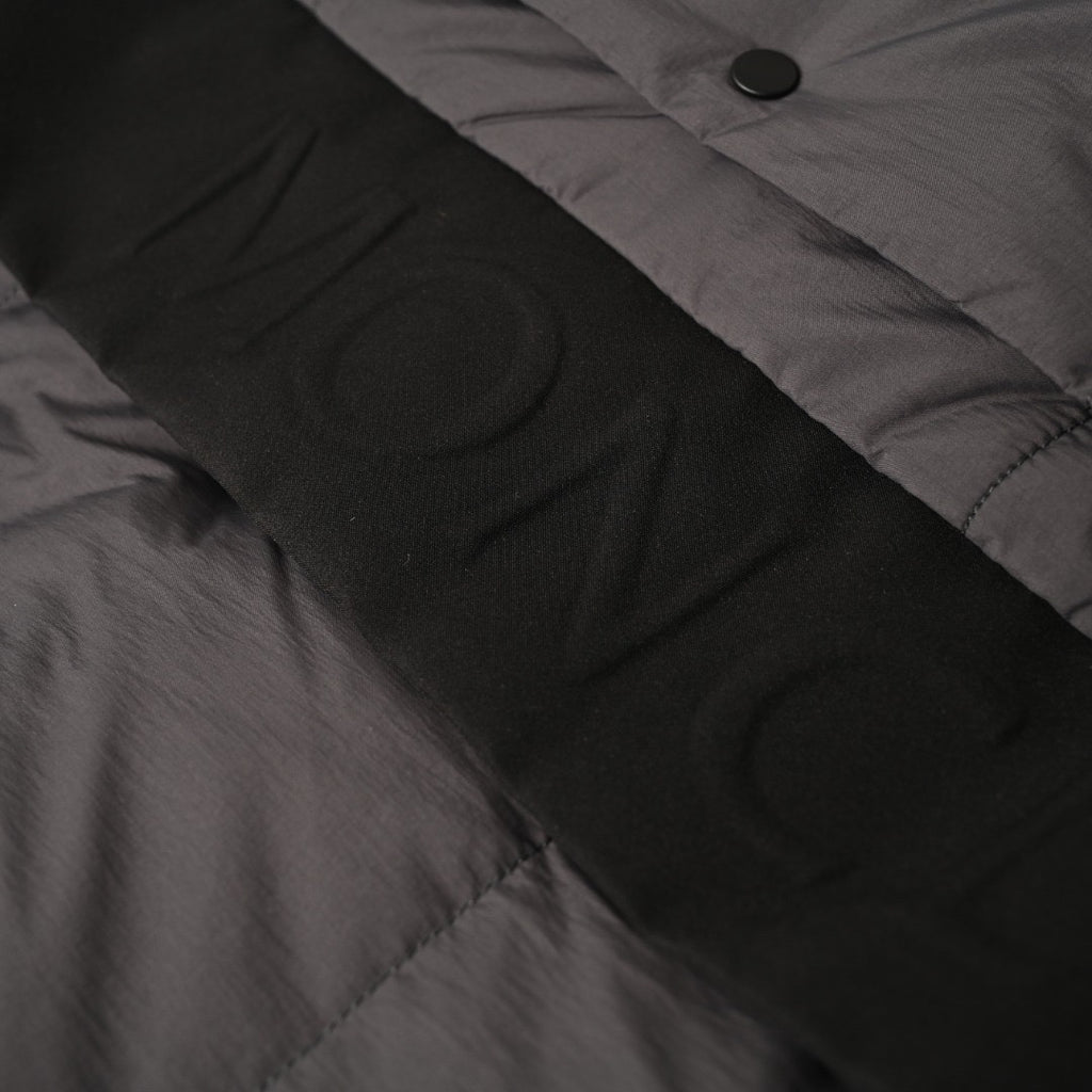 Long puffer jacket fabric close-up with button placket and seam detail