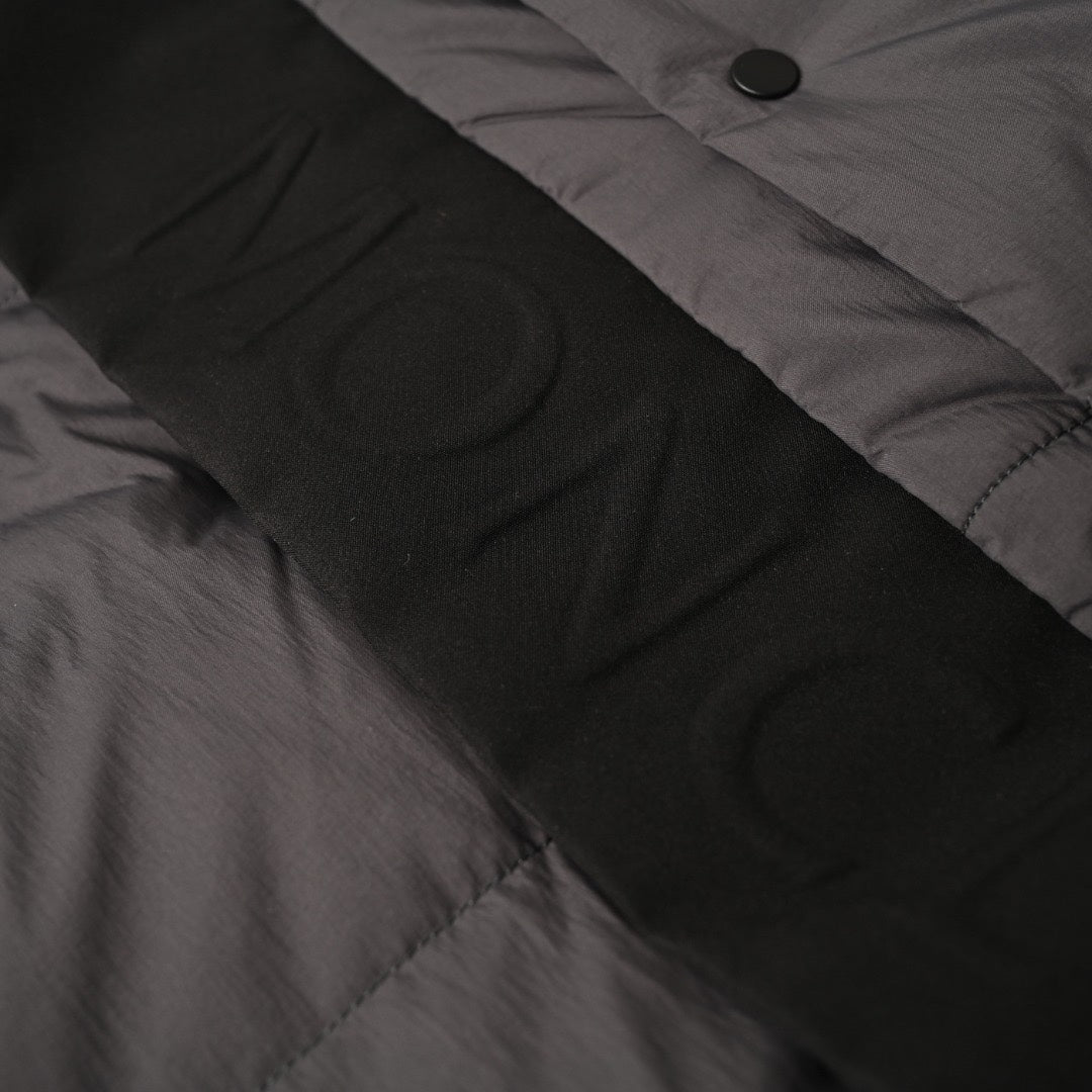 Long puffer jacket fabric close-up with button placket and seam detail
